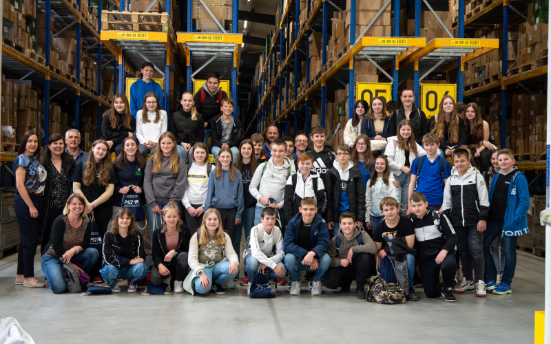 Gruppenfoto der Sch&uuml;lerinnen und Sch&uuml;ler der Realschule Vohenstrau&szlig; zwischen den Regalen im Lager