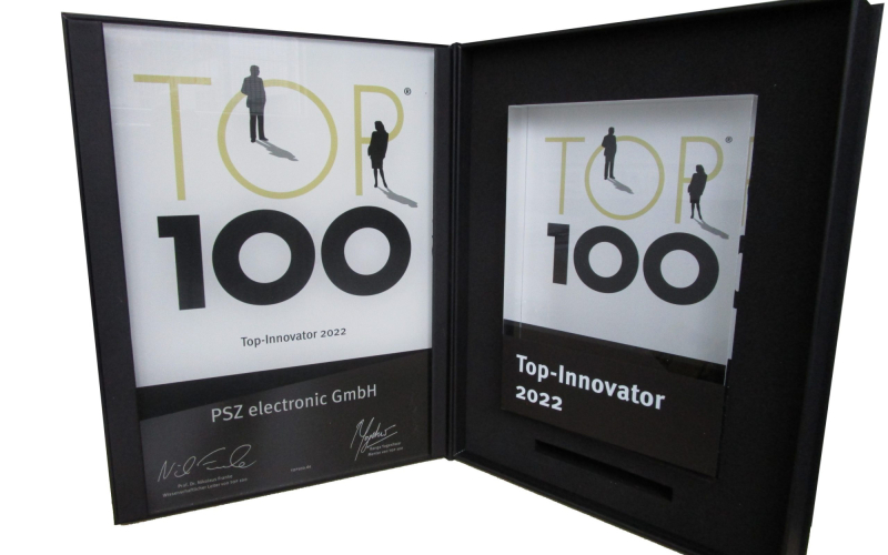 Urkunde und Glastroph&auml;e &bdquo;Top 100 Top-Innovator 2022&ldquo; f&uuml;r die PSZ electronic GmbH in einer aufgeklappten Box