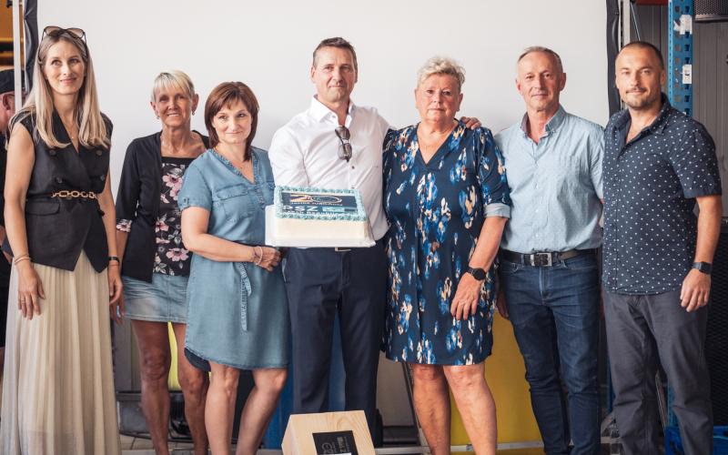Gruppenfoto von acht Personen mit der Torte zum 20-j&auml;hrigen Jubil&auml;um des tschechischen Standorts