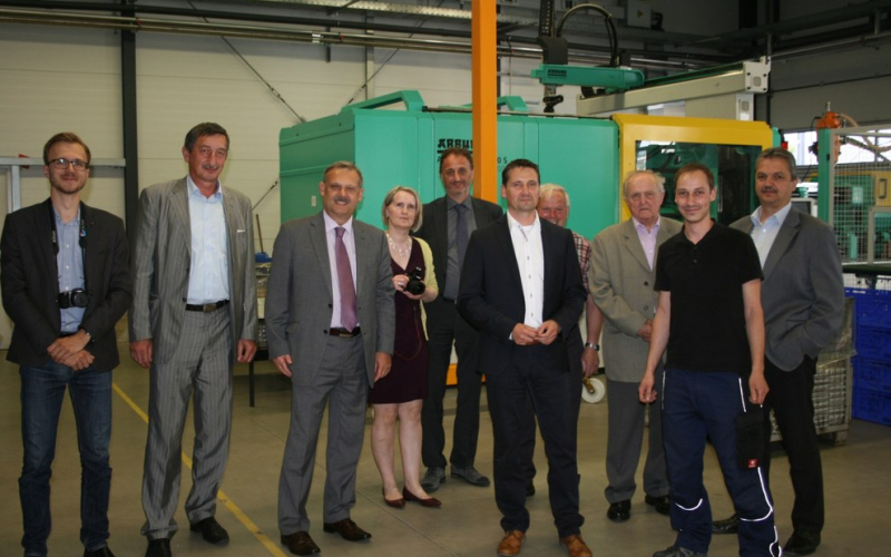 Gruppenfoto mit der tschechischen Delegation in der Fertigungshalle vor einer Spritzgussmaschine