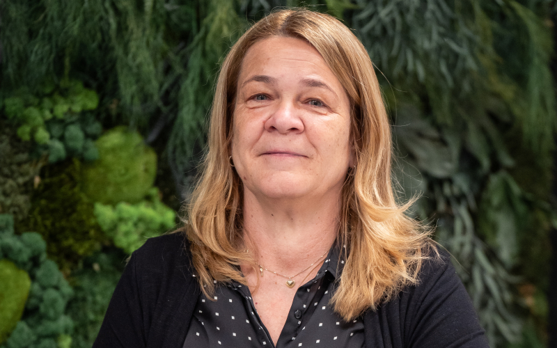 Annette Rieck-Silio, Head of HR, auf einem Sofa vor einer Pflanzenwand